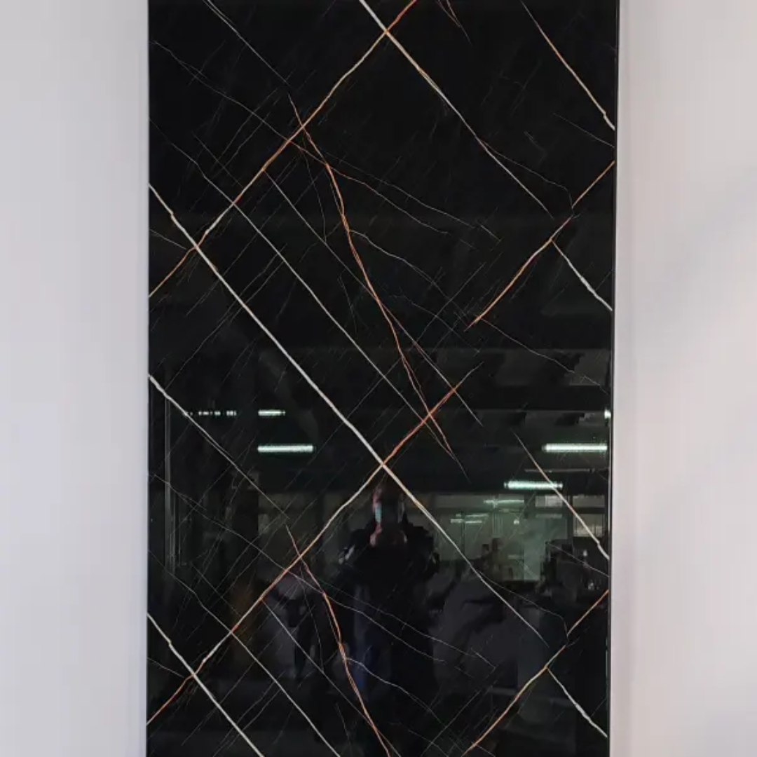 A rectangular black marble-look panel or mirror with elegant copper and white veining, mounted on a light gray wall. The reflective surface shows a dark interior reflection with ceiling lights and a person holding a camera.